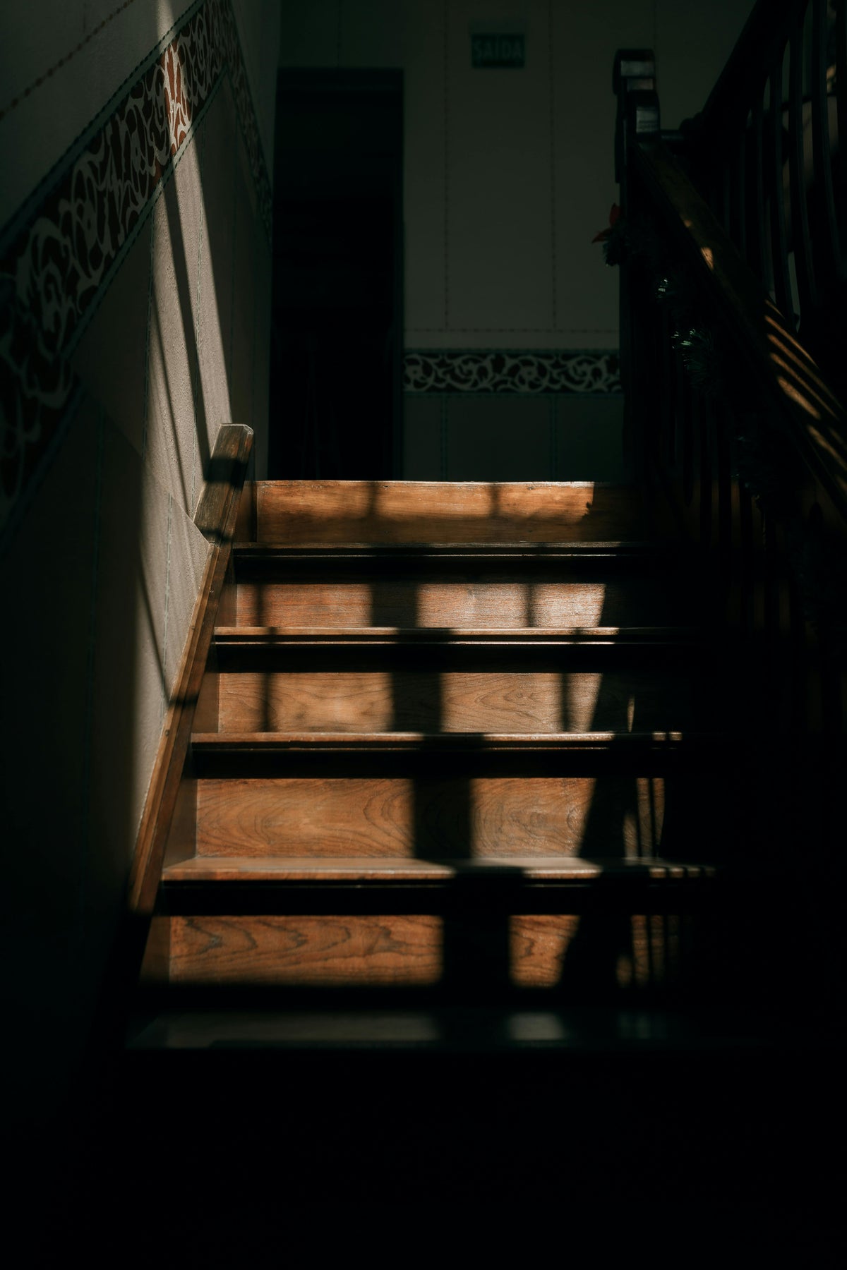 Black metal handrail installed on wooden stairs with white wall background